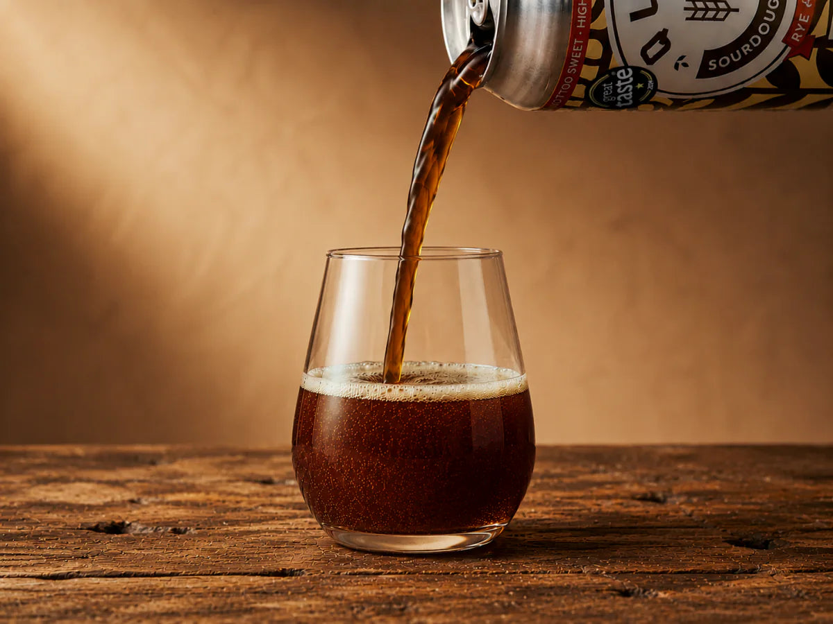 Quas being poured from the can into a stemless tulip glass
